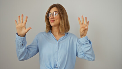 Attractive blonde woman in blue shirt showing the number nine with fingers over isolated white...