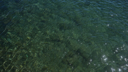 Crystal clear water ripples over rocky seabed at pescoluse beach in salento, puglia, italy, displaying sunlight reflection in this serene outdoor scene.
