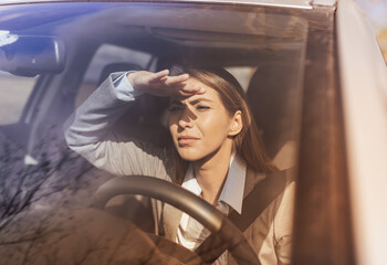 Woman driving car while sun blinding view