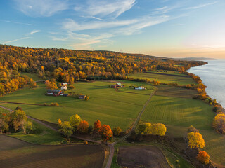 Autumn rural landscape in Sweden near Gränna, from above with vibrant colors and large open fields, at sunset. Orange, yellow and green trees, green open fields, red houses.