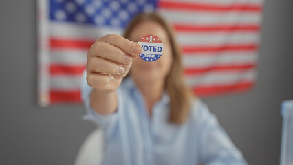 Adult woman displays 'i voted' sticker with american flag in background symbolizing civic duty and...