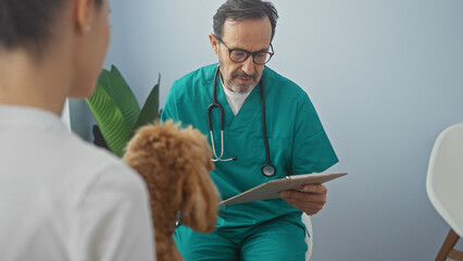 Hispanic veterinarian man examines a poodle in a clinic, indicating healthcare for pets indoors.