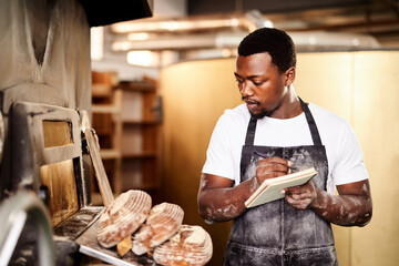 Black man, bread and notes for baker, small business owner and pastry kitchen workshop. African...