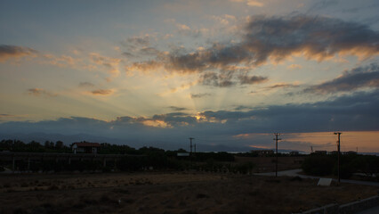 Golden rays break through the clouds over a tranquil landscape at dusk, casting gentle shadows on...