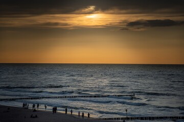 Silhouettes of birds flying over the sea during sunset. The coast of the Baltic Sea in Mielno, Poland.