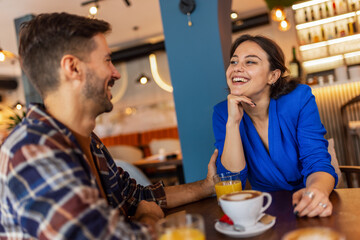 Couple on a date in a cafe. They drink coffee and orange juice.