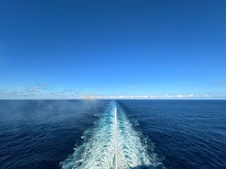 Wide angle view of the ocean behind a cruise ship with copy space for text in the blue sky