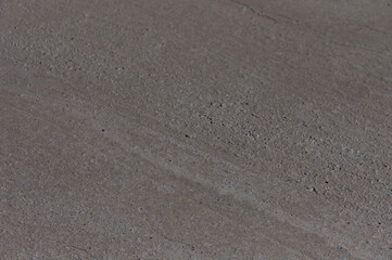 A close-up view of textured concrete surface capturing intricate details and shadows under natural...