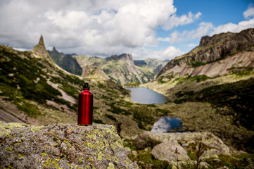 a red tourist bottle in the mountains on the background of a beautiful lake