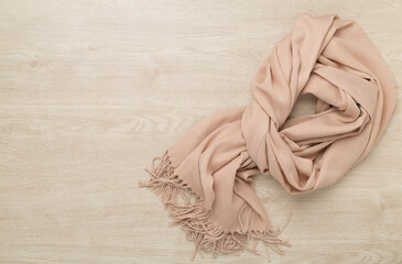 Stylish scarf on wooden background, top view