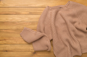Brown sweater on wooden background, top view