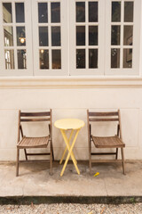 Yellow table and wooden chairs at cozy house or restaurant in garden,modern home decor,Contemporary interior design of dining space,minimal concept.