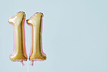 Gold number 11 balloons with pastel pink and blue balloons for eleventh birthday party celebration, event decoration, or festive party design with a simple and elegant style