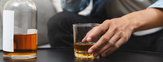melancholy young Asian man drinks alcoholic whisky alone at home feeling dizzy after drunk