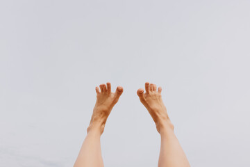 Legs up in the air against a blue sky, showcasing bare feet