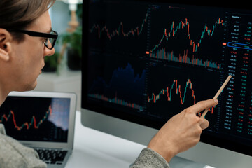 Smart stock investors pointing interesting market stock exchange on pc with laptop screen. Financial technology dynamic investment plan focusing data graph on monitor at modern workplace. Pecuniary.