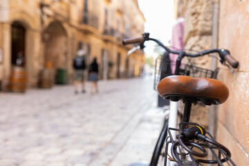 Old bicycle saddle with blurred background on cobblestone street in the old town of Ciutadella,...