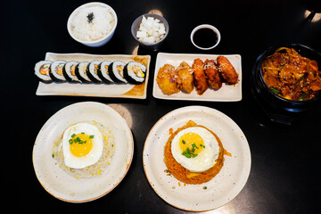 Korean foods served on a dining table,Gimbap,Fried chicken, radish,kimchi,spicy sauce with rice, seaweed,bibimbap,kimbap,Kimchi fried rice with fried egg and scallion sprinkle,copy space.