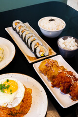 Korean foods served on a dining table,Gimbap,Fried chicken, radish,kimchi,spicy sauce with rice, seaweed,bibimbap,kimbap,Kimchi fried rice with fried egg and scallion sprinkle,copy space.
