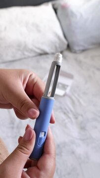 A vertical close up of a young woman holding the pen injector in her hands