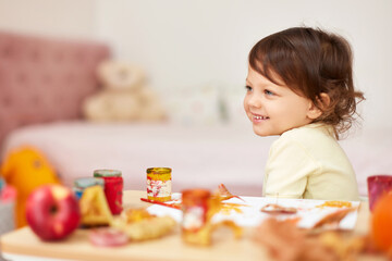 happy little child girl painting autumn leaves. baby girl drawing leaves in yellow paint