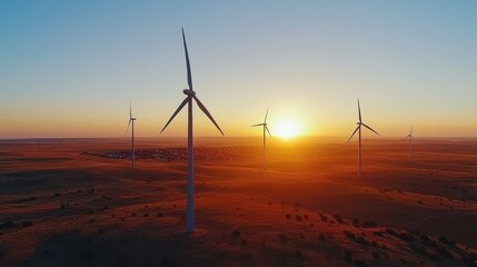 Obraz premium Scenic view of wind turbines in a rural landscape at sunset with rolling hills and vibrant sky.