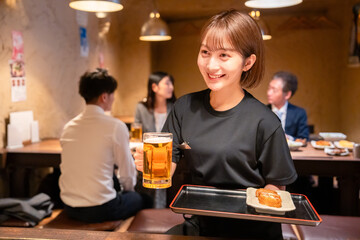 ビールを提供する居酒屋の女性スタッフ
