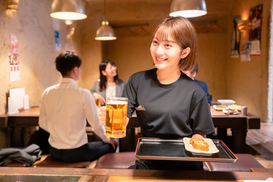 ビールを提供する居酒屋の女性スタッフ