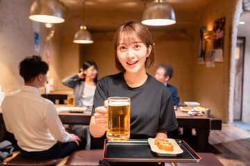 ビールを提供する居酒屋の女性スタッフ