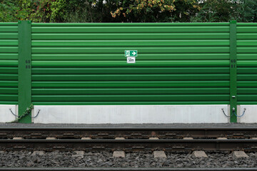 Grüne Lärmschutzwand an Bahnstrecke mit Schild Notausgang 50m - Stockfoto
