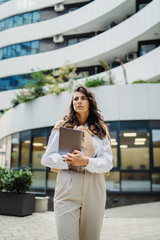 Fototapeta premium Young businesswoman going to work in front of modern business building