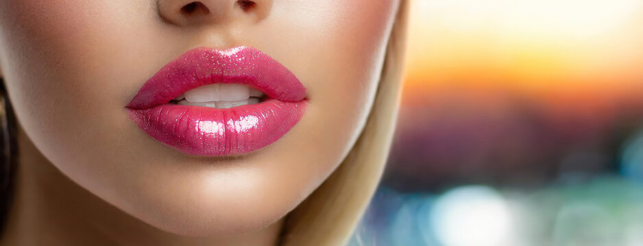 Close-up of glossy pink lips of a woman. Panorama.
