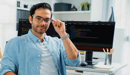 Profile's smart IT developer looking camera to pose wearing glasses against on software development...