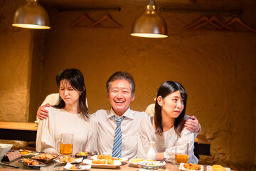 宴会の席で女性と肩を組むビジネスマン