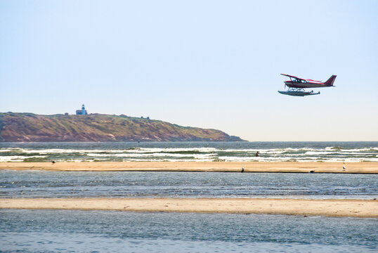 Low flying seaplane over Popham State Park Beach, Maine, with Seguin Island and lighthouse in background