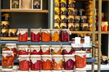 A bright, original shelf with jars of various salted canned vegetables and berries.