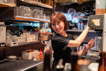 飲食店でビールサーバーを使う女性の店員