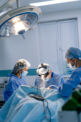 Surgeons conduct delicate surgery in bright room. A team of surgeons is focused on a critical...