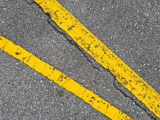 Fototapeta premium two thick old yellow painted lines on gray asphalt