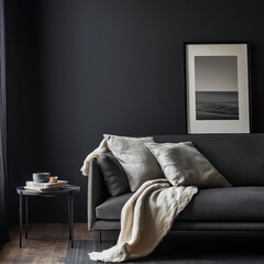 A black couch with two pillows and a white blanket on it
