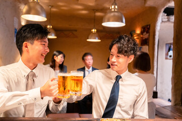 居酒屋でビールを飲む二人の若手ビジネスマン