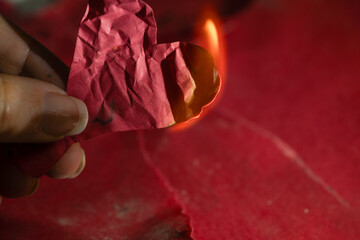 mano sosteniendo corazón de papel en llamas