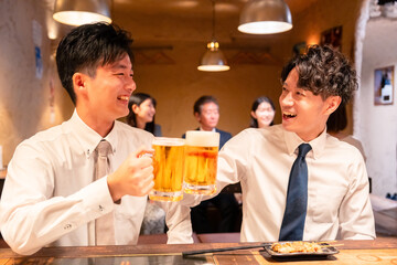 居酒屋でビールを飲む二人の若手ビジネスマン