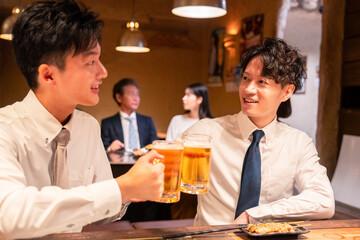 居酒屋でビールを飲む二人の若手ビジネスマン