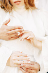 Newlyweds exchange rings, groom puts the ring on the bride's hand.