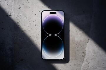Smartphone on Concrete: Sleek smartphone rests on a textured concrete surface, bathed in dramatic light.  The minimalist design and vibrant screen capture attention. 