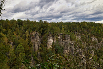 Fototapeta premium Bewaldete Sandsteinfelsen im herbstlichen Mischwald, Blick auf markante Felsnadeln im Nationalpark Sächsische Schweiz, Sachsen, Deutschland