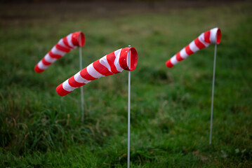 three red and white windsocks in a meadow