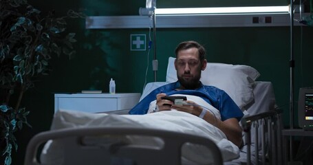 Sick man is playing games on his phone, having fun and relaxing while receiving treatment. - Powered by Adobe