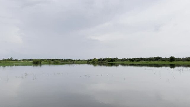 Floating on boat on calm water of a river in cloudy weather